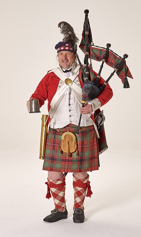 Quest in historischer schottischer Uniform mit einem Zinn-Humpen in der Hand und Highland-Bagpipes über der Schulter